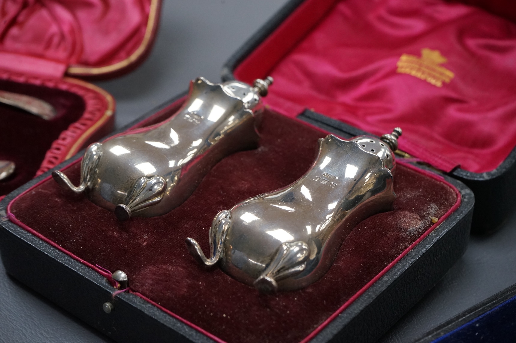 Three cased silver items including an Edwardian christening trio, a pair of George V pepperettes, Birmingham, 1916 and a George V pierced silver oval mustard pot, Birmingham, 1916.